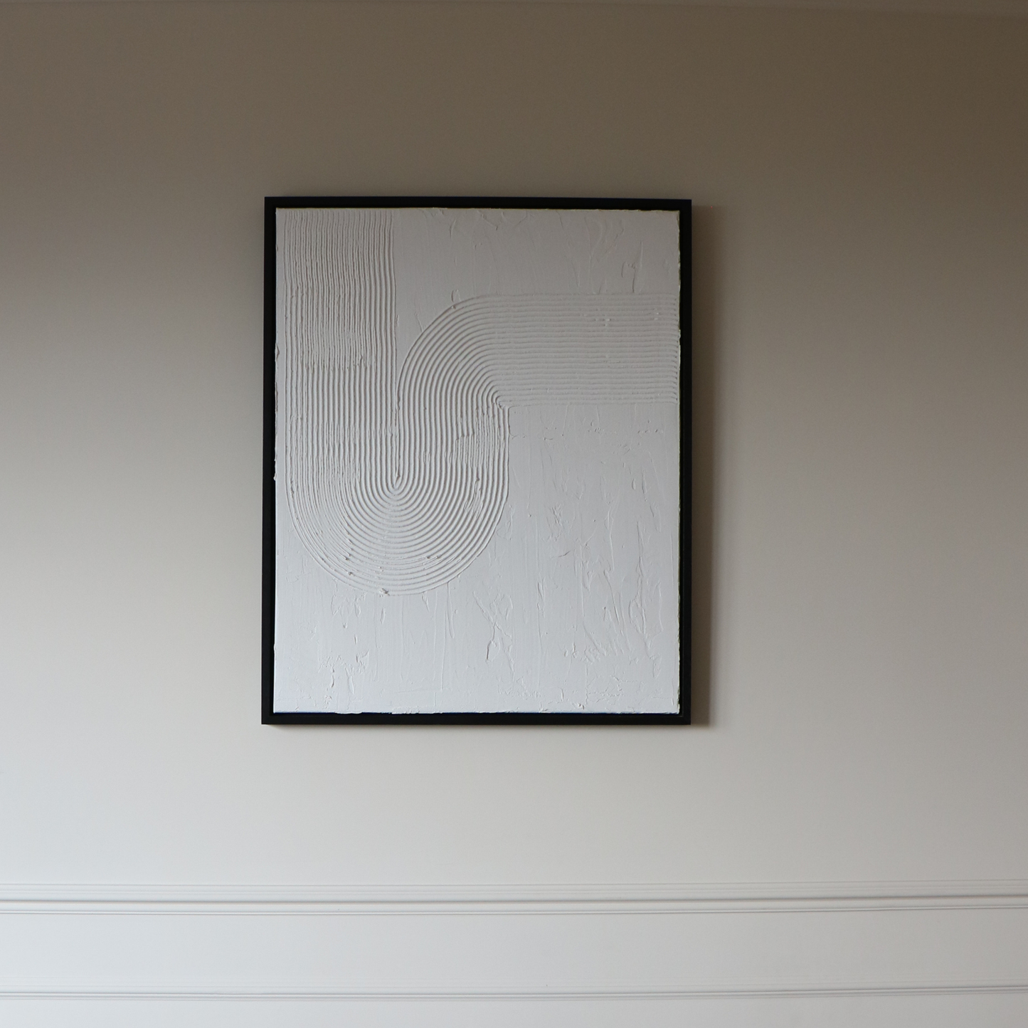 Abstract textured artwork on a plain wall in black frame