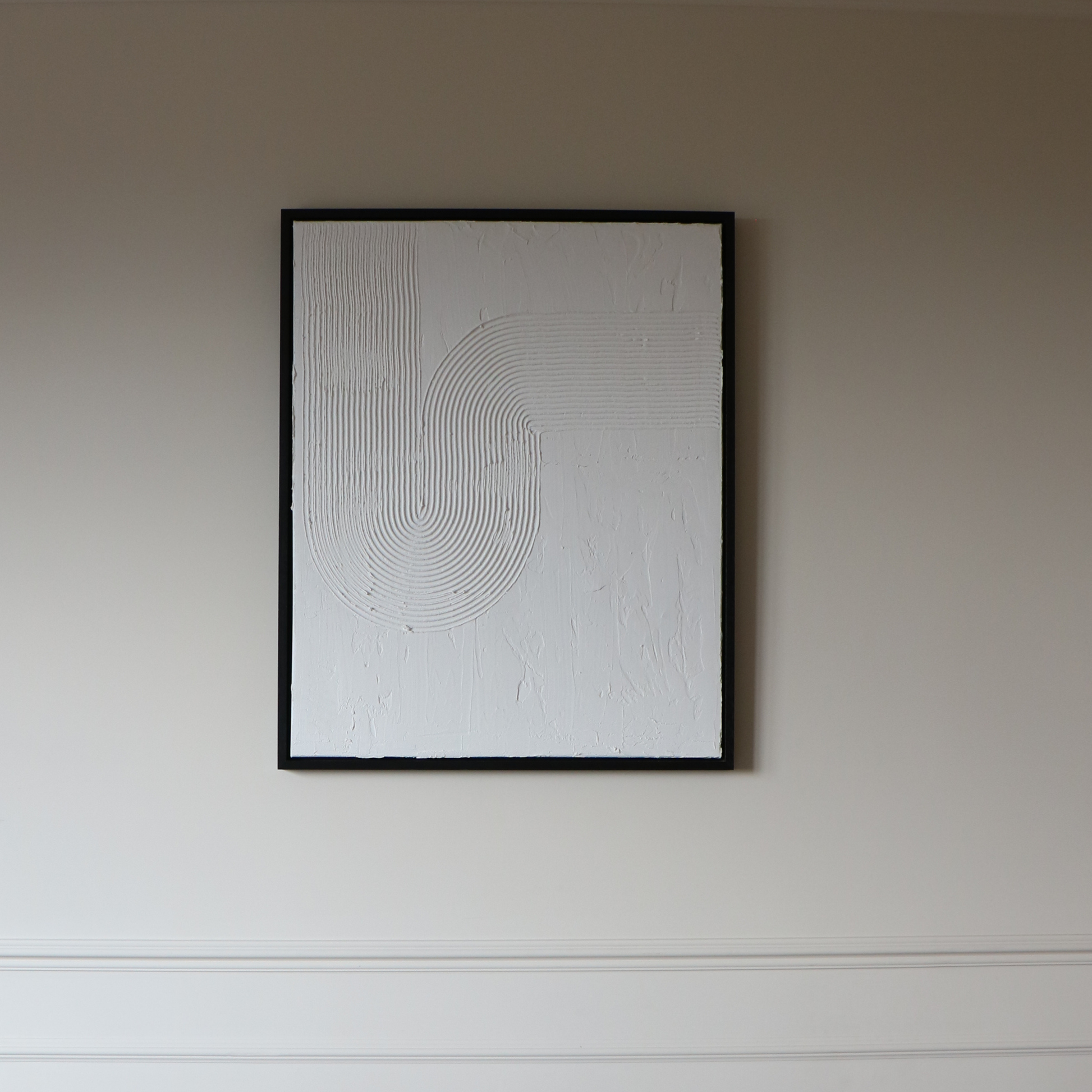 Abstract textured artwork on a plain wall in black frame