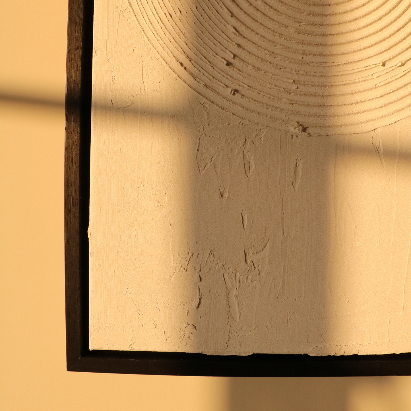 Abstract textured artwork on a plain wall in black frame