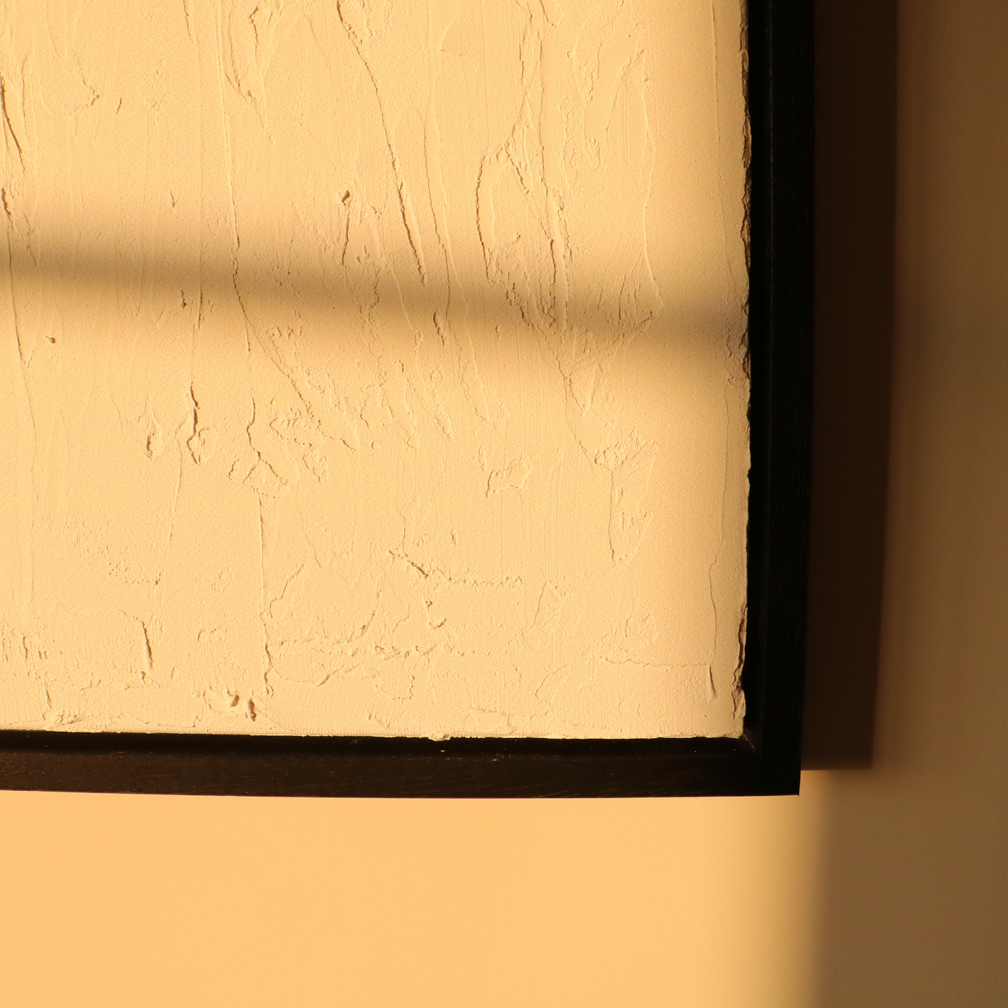 Abstract textured artwork on a plain wall in black frame